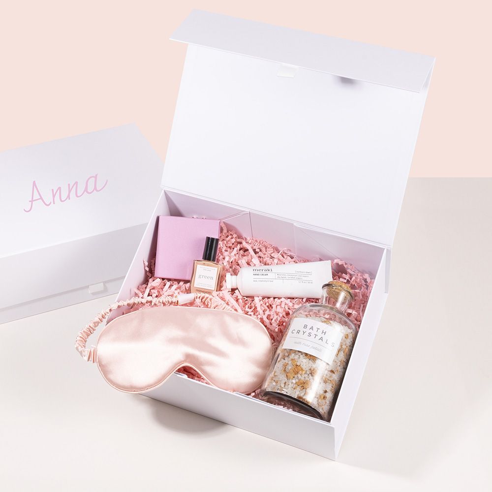 White hamper box with pink filler, and toiletries with sleeping mask