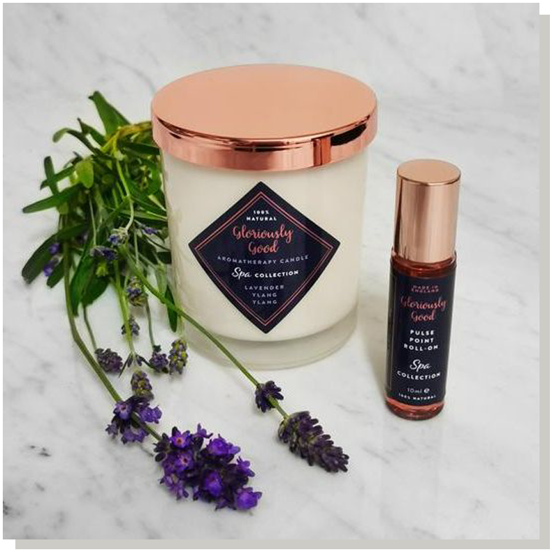 candle with a rose gold coloured lid and a roll on scent standing side by side with some lavender next to the products